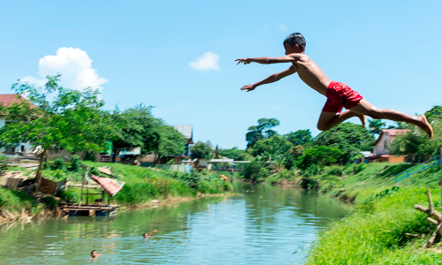 Criança pulando em um rio