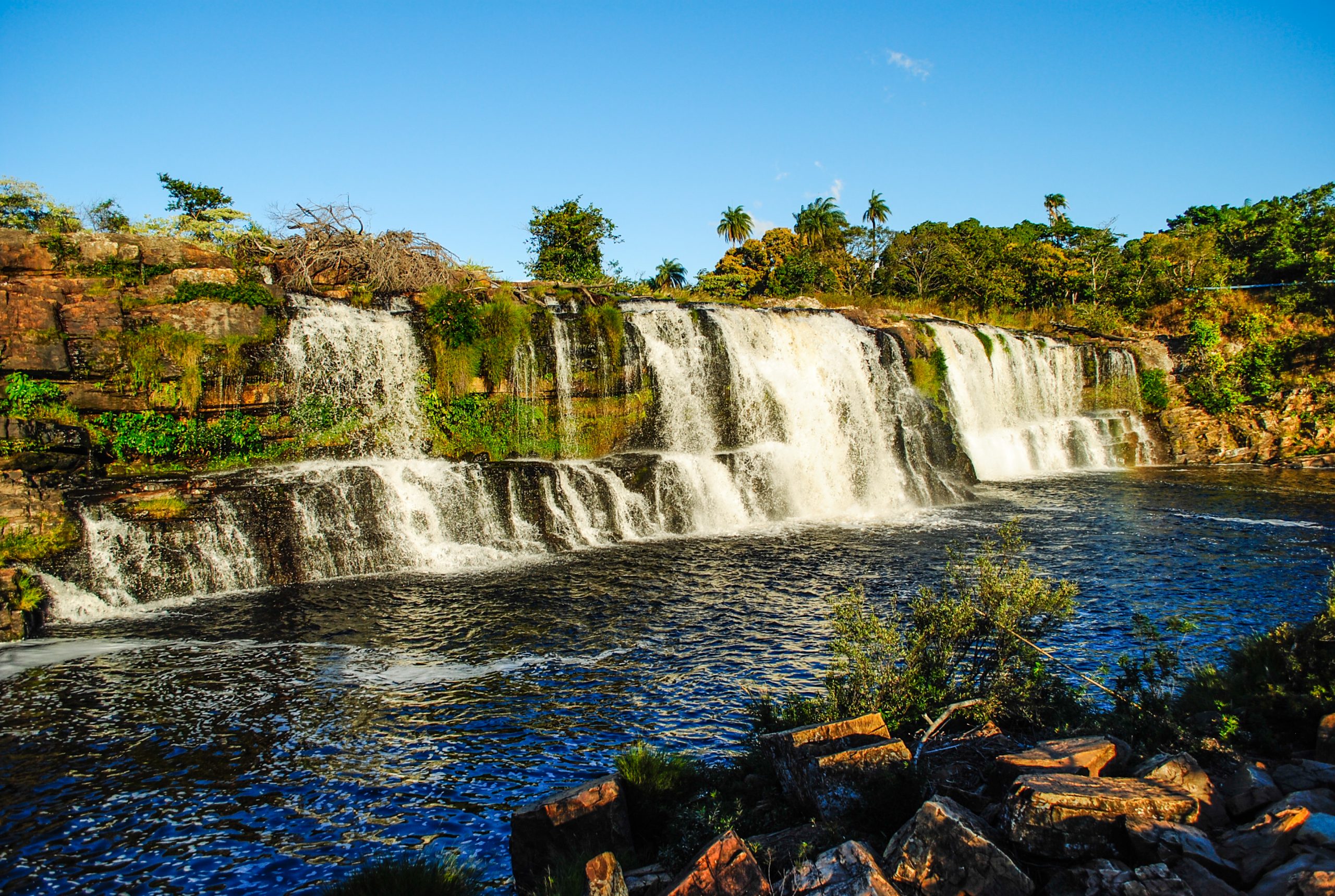 Foto de uma cachoeira rodeada de vegetação no Parque Nacional da Serra do Cipó.