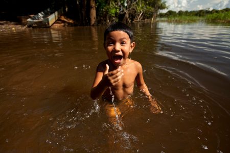 Criança indígena brincando em rio no Tocantins. Fundo Amazônia.