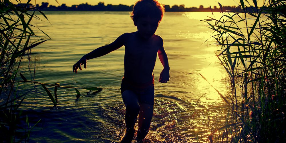 Silhueta de uma criança correndo na margem de um rio. Ao fundo, o pôr do sol. Lei Mais Urgente do Mundo