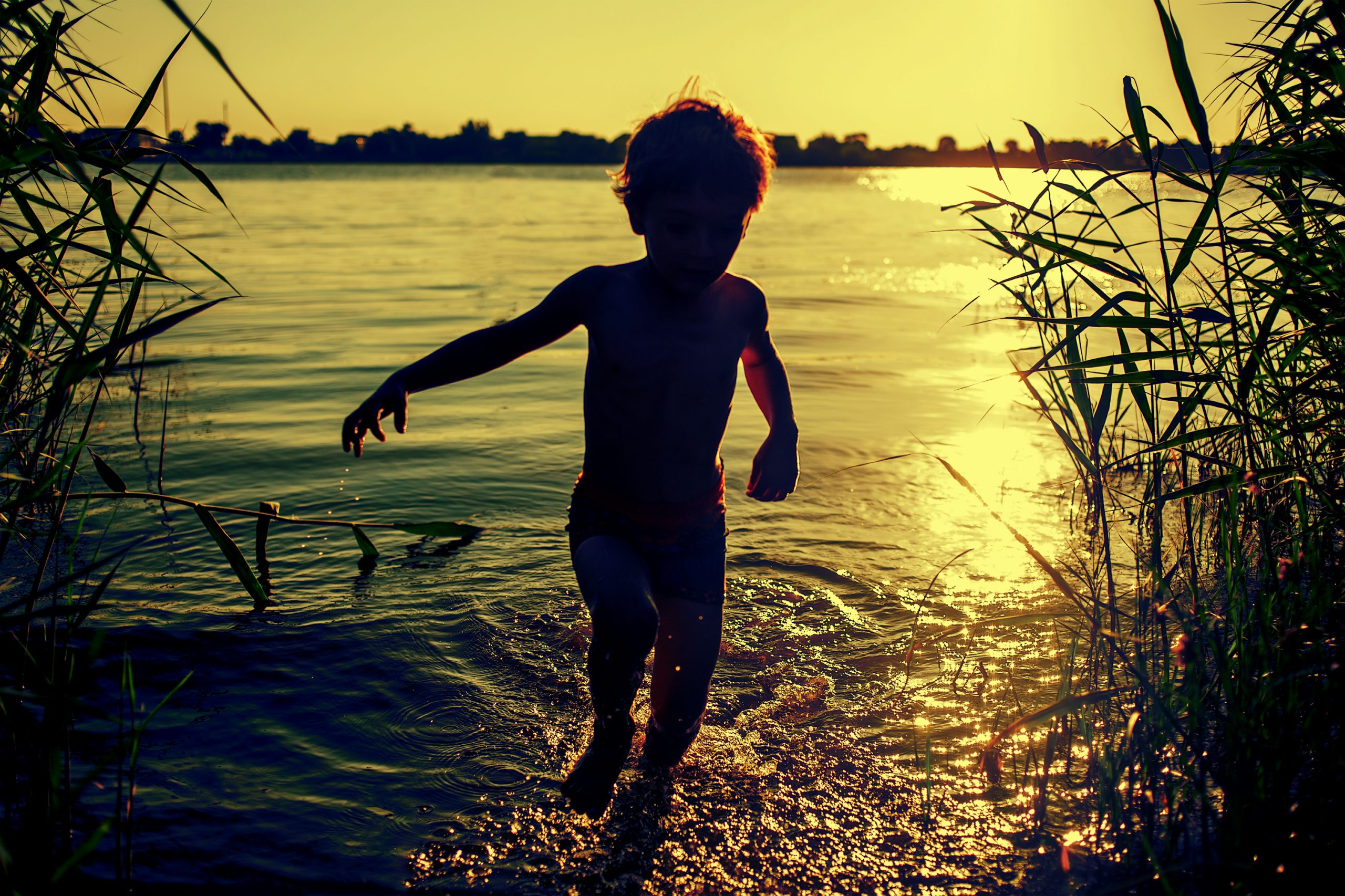 Silhueta de uma criança correndo na margem de um rio. Ao fundo, o pôr do sol. Lei Mais Urgente do Mundo