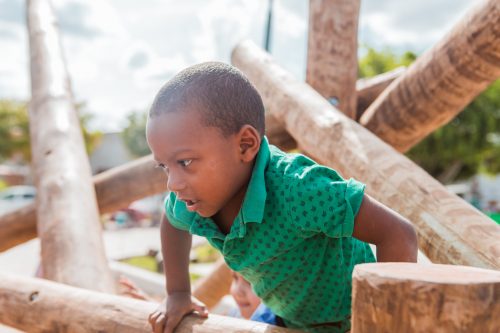 Criança escalando um brinquedo feito com madeiras. Parque Naturalizado em Caruaru.