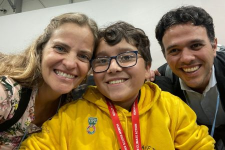 Imagem de Francisco Vera, usando óculos e um casaco amarelo. Ao seu lado estão Laís Fleury e JP Amaral, do Instituto Alana.