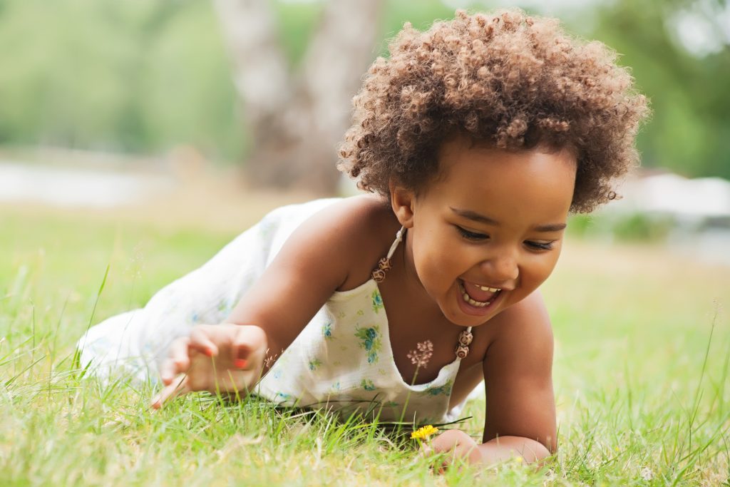 [:pt]Criança sorrindo e brincando na grama. COP 27.[:]