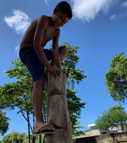 Criança escalando um brinquedo feito de madeira, que integra o guia de brinquedos naturais.